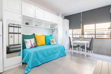 - une chambre avec un lit doté d'oreillers colorés et d'une table dans l'établissement Estudio W&G Las Canteras con bonitas vistas al mar, à Las Palmas de Gran Canaria
