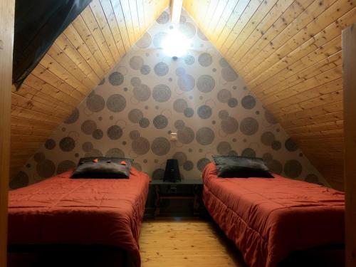 Zimmer im Dachgeschoss mit 2 Betten mit roter Bettwäsche in der Unterkunft Appartement dans chalet avec jardin, vue montagne in Aucun