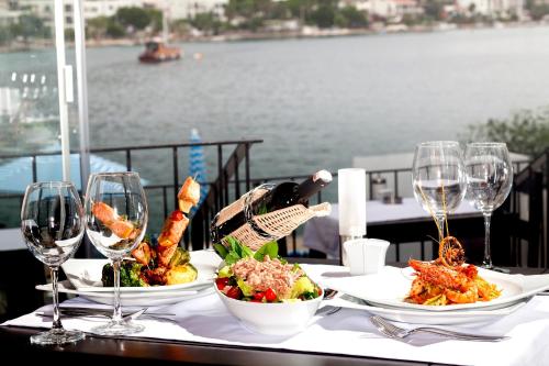 a table with two plates of food and wine glasses at Zena Hotel Bodrum in Guvercinlik