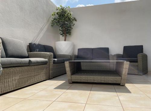 Un patio con sillas de mimbre y una mesa. en Rock Bay, en Birżebbuġa