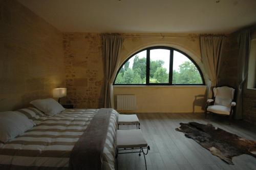 um quarto com uma cama e uma grande janela em Gîte de charme à 15mn de Bordeaux Autonomie 100% em Camblanes-et-Meynac