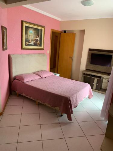 a bedroom with a pink wall and a bed at Cobertura frente ao mar Meia Praia -Itapema -SC in Itapema
