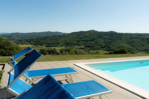 a swimming pool with two blue chairs and a swimming pool at Agriturismo Villa Lugnano Casale Con Piscina Privata in Lugnano
