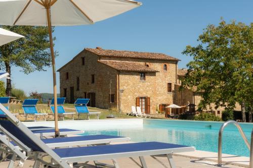 una piscina con sillas y una sombrilla y un edificio en Agriturismo Villa Lugnano Casale Con Piscina Privata, en Lugnano