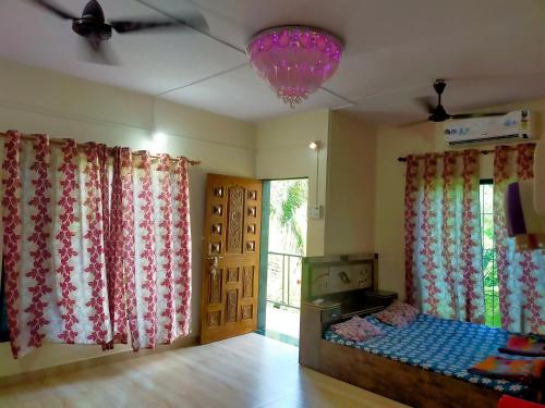 a bedroom with curtains and a bed and a window at Sai Sneh Holidays Cottage in Alibaug