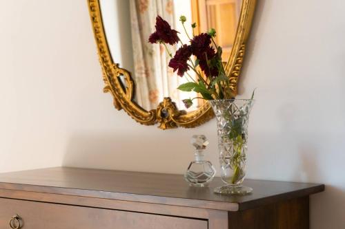 a vase with flowers on a table in front of a mirror at Agriturismo Villa Lugnano Casale Con Piscina Privata in Lugnano