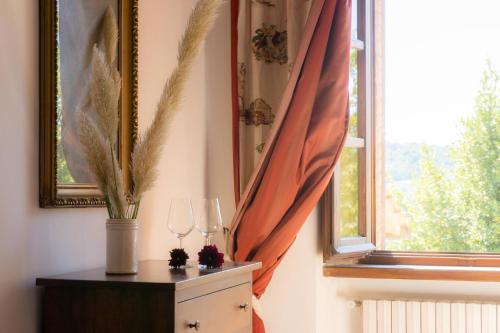 a window with an orange curtain and a dresser with glasses at Agriturismo Villa Lugnano Casale Con Piscina Privata in Lugnano