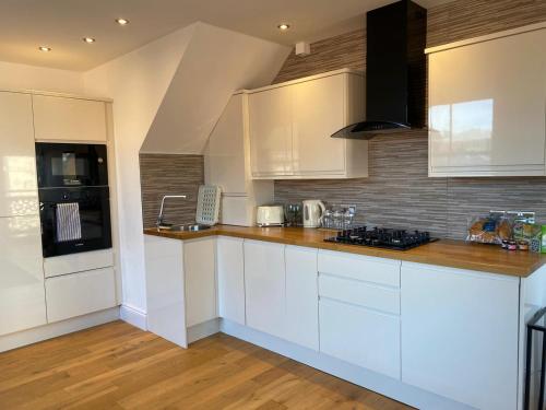 a kitchen with white cabinets and a wooden floor at City Centre Duplex Sleeps 4 #H9 in Hull