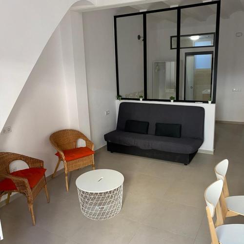 sala de estar con sofá negro y sillas en Loft Cabanyal, en Valencia