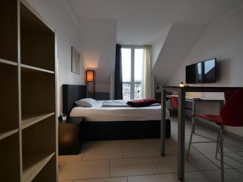 a bedroom with a bed and a desk and a television at Rooftop Apartment by Rabe - Parkplatz & free Netflix & Balkon in Karlsruhe
