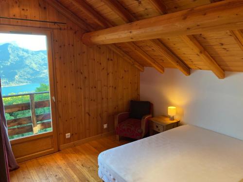 une chambre avec un lit et une grande fenêtre dans l'établissement Chalet bioclimatique avec vue sur le lac de Serre Ponçon, à Saint-Apollinaire