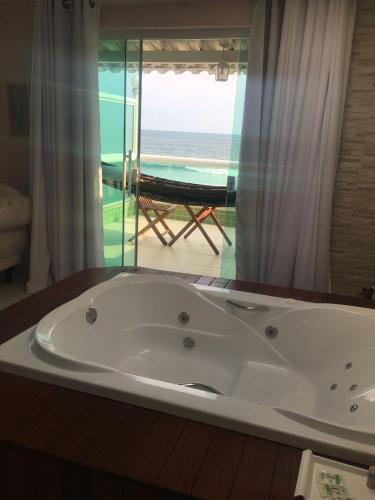a bath tub with a view of the ocean at Hotel Aconchego Da Vila in Saquarema