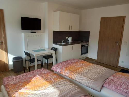 Habitación con 2 camas, mesa y cocina. en Heimatliebe Bruckmaier, en Neustadt an der Donau