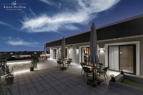 a patio with tables and chairs and an umbrella at Khan Duidar Inn - Pyramids View Rooftop in Cairo