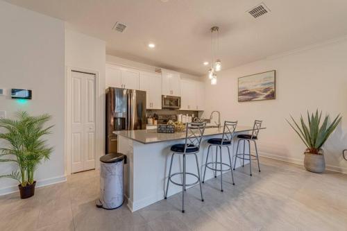 a kitchen with a counter with stools and a refrigerator at NEWLY LISTED Townhouse Storey Lake, Free Waterpark in Kissimmee