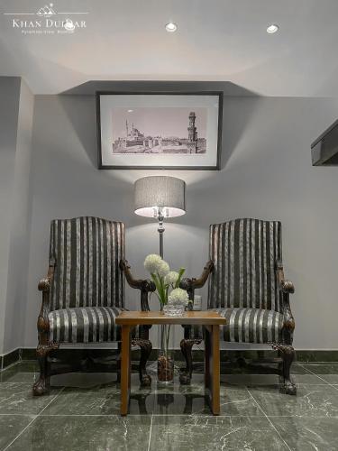 two chairs and a table with a lamp in a room at Khan Duidar Inn - Pyramids View Rooftop in Cairo