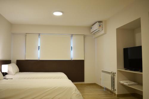 a bedroom with two beds and a window with a television at Hotel Bait in General Roca