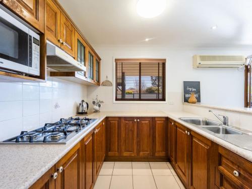 a kitchen with wooden cabinets and a sink and a stove at Bundjalung and Baby Bundjalung in Iluka