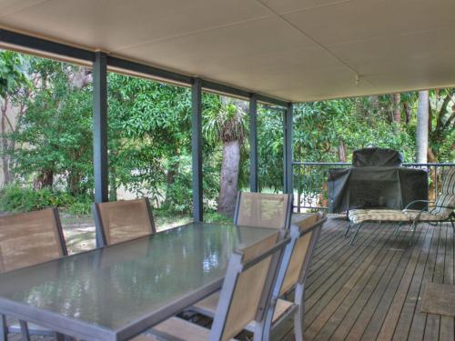 a table and chairs on a deck with trees at Bayview at Iluka in Iluka