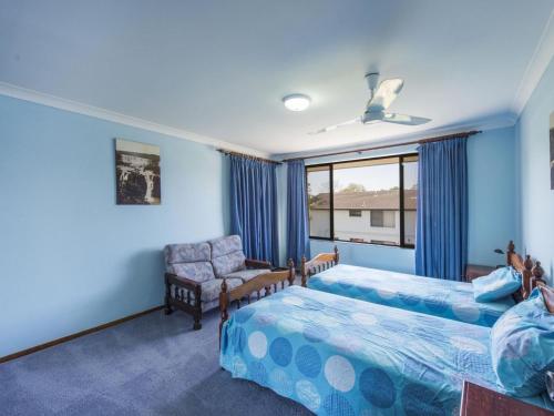 a bedroom with two beds and a chair and a window at Camawood 11 Iluka NSW in Iluka