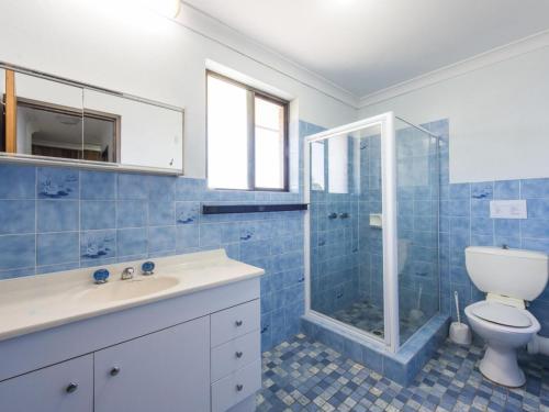 a blue tiled bathroom with a toilet and a shower at Camawood 11 Iluka NSW in Iluka