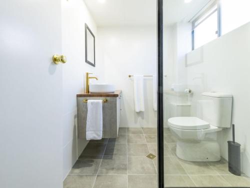 a white bathroom with a toilet and a sink at Iluka Villa 2 in Iluka