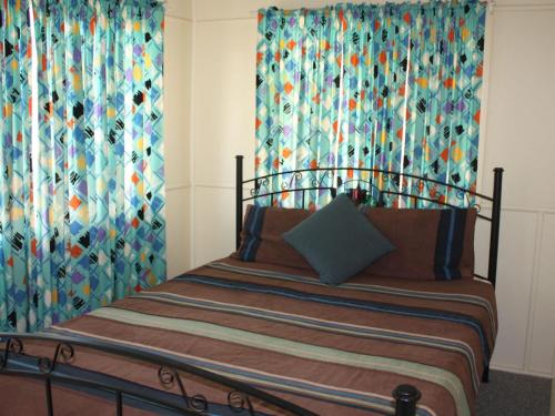 a bedroom with a bed with colorful curtains at Luka Land in Iluka