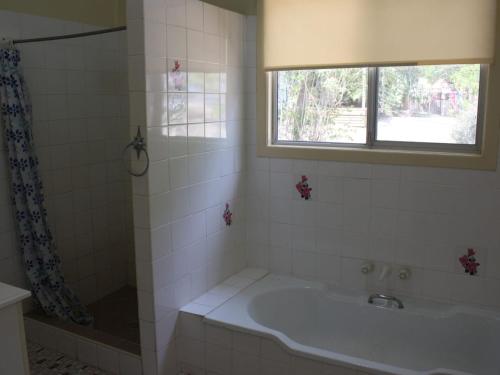 a bathroom with a tub and a sink and a window at Luka Land in Iluka