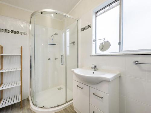 a white bathroom with a shower and a sink at Salt Water Cottage in Iluka