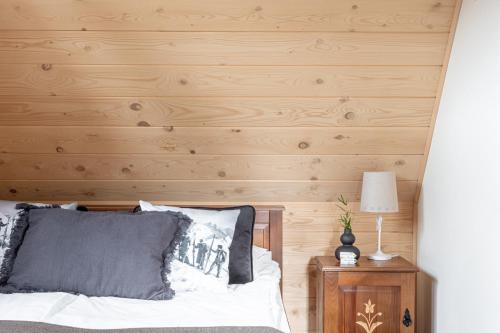 - une chambre avec un lit et un mur en bois dans l'établissement Jochymówka Zakopane, à Zakopane