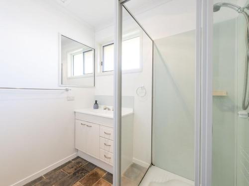 a white bathroom with a shower and a sink at Sandy Feet in Iluka