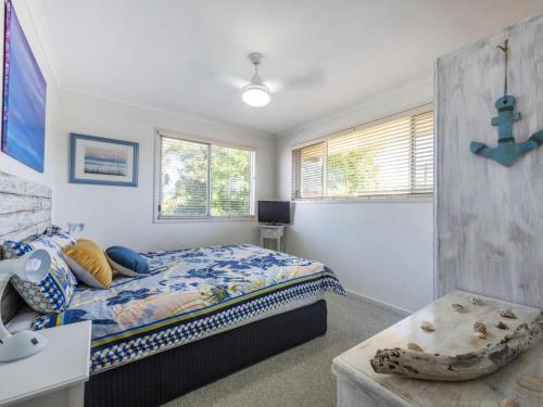 a bedroom with a bed and a desk and windows at Sandy Feet in Iluka