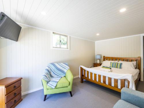 ein Schlafzimmer mit einem Bett und einem grünen Stuhl in der Unterkunft The Net Shed in Iluka
