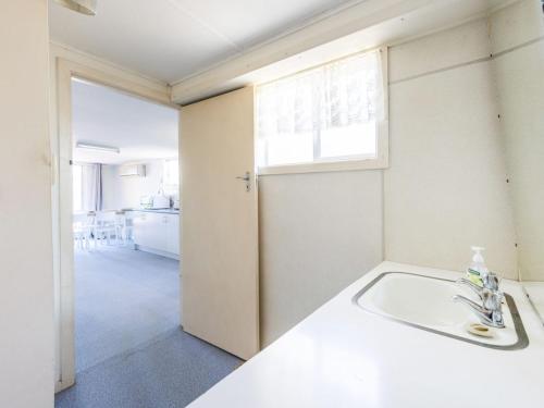 a white bathroom with a sink and a window at The Net Shed in Iluka