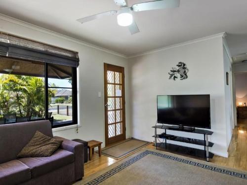 a living room with a couch and a flat screen tv at Tarraloo Iluka NSW in Iluka
