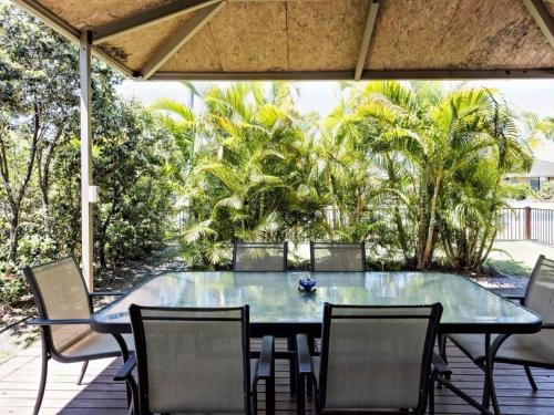 a blue table and chairs on a deck with trees at Tarraloo Iluka NSW in Iluka