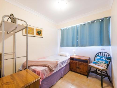 a small bedroom with a bunk bed and a chair at Unit 4 Orana in Iluka