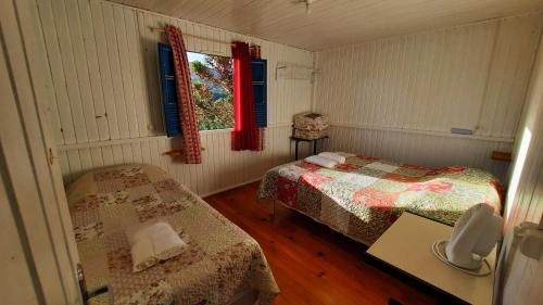 um quarto com duas camas e uma mesa e uma janela em Casinha de campo rural em Urubici