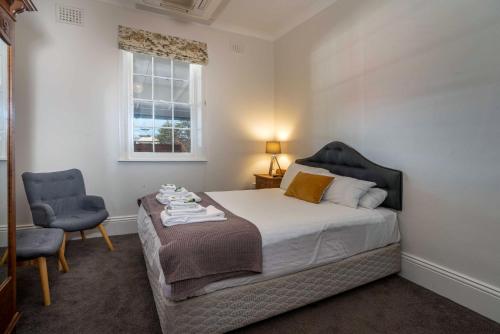 a bedroom with a bed and a chair and a window at Metropolitan Hotel in Orange