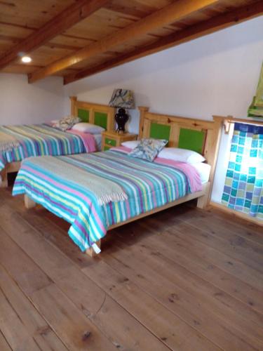 two beds in a room with wooden floors at Hermosa y cálida casa tipo cabaña in Creel