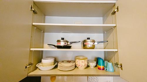 a cupboard with dishes and pots and pans at Genting Premium Suite Windmill Upon Hills by JAz Home Suites in Genting Highlands