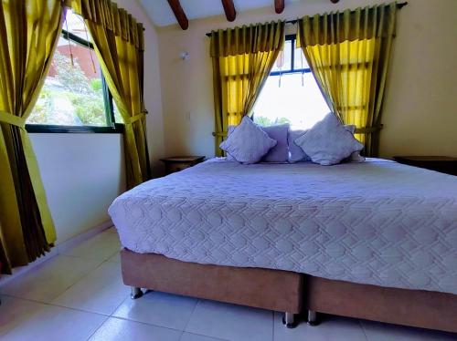 a bedroom with a large bed with yellow curtains at Hotel Cabañas San Cayetano in Paipa