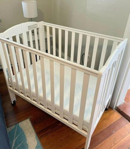 a white crib in a room with a lamp at The Lafayette House in Mobile