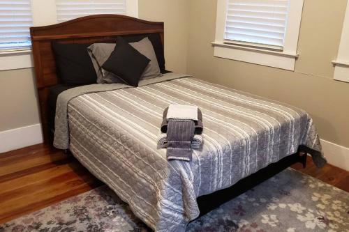 a bedroom with a bed with a blanket and two windows at The Lafayette House in Mobile