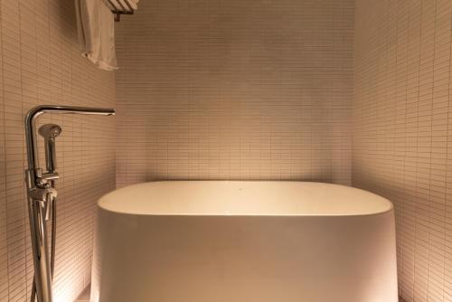 a white tub in a white tiled bathroom at Greet Inn in Kaohsiung