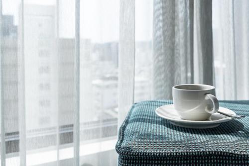a cup of coffee sitting on a table next to a window at Greet Inn in Kaohsiung