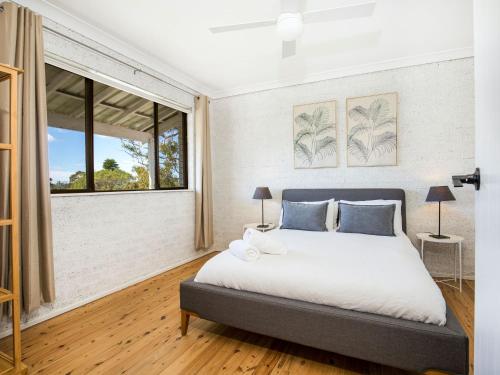 a bedroom with a large bed and a window at Whitewash I Pet Friendly I 5 Mins Walk to Beach in Callala Beach