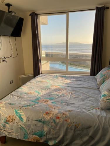 a bedroom with a bed with a large window at Laguna del mar La Serena in La Serena