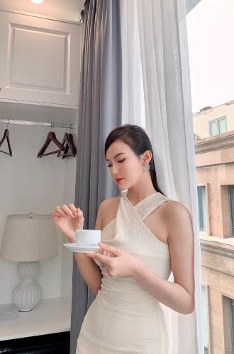 a woman in a white dress holding a cup of coffee at Opera House Suites in Hanoi