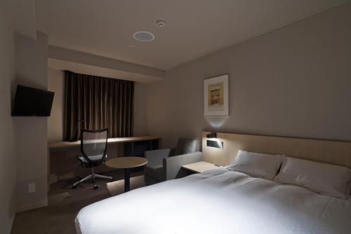 a hotel room with a bed and a table and chairs at Rhino Hotel Kyoto in Kyoto